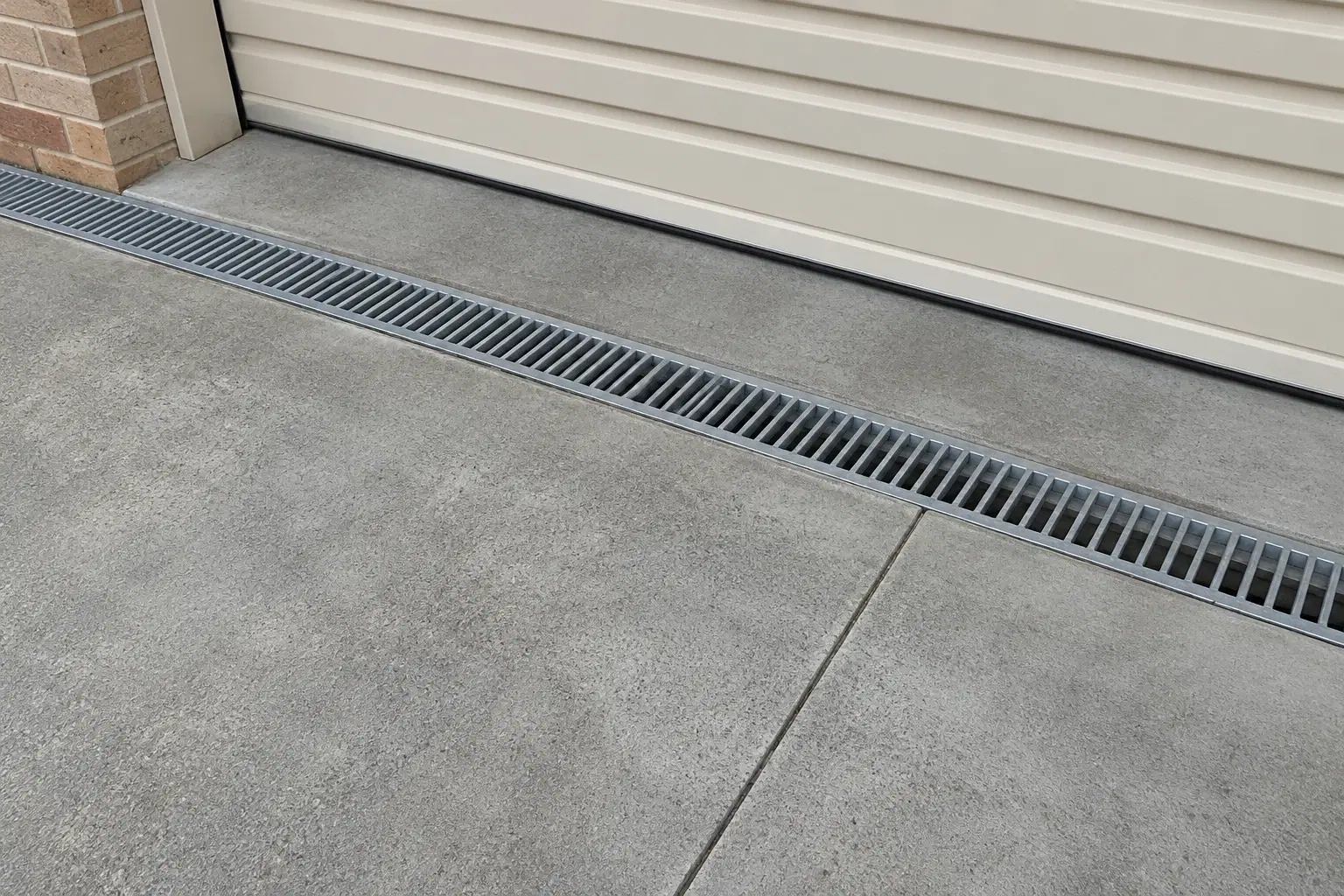 Design concept of a driveway channel drain outside a brick garage